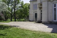 a bike parked in front of an old mansion building on the grass in front of it is an empty path