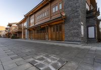 a stoned street in an asian - like neighborhood with old buildings and gated streets