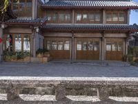 the entrance to a large old chinese home in stone walls and wood doors with a wooden roof