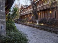 a stone sidewalk surrounded by houses and trees with lamps on it's sides in a town setting