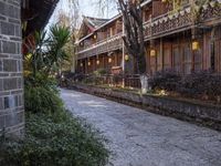 a stone sidewalk surrounded by houses and trees with lamps on it's sides in a town setting