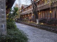 a stone sidewalk surrounded by houses and trees with lamps on it's sides in a town setting