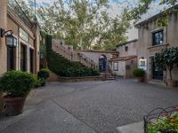 a courtyard with stairs and outdoor seating in the background with trees and buildings on both sides