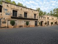 an empty brick lot with two parked motorcycles in front of a building and plants and trees