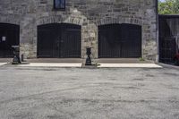 an older stone building with garage doors and two fire hydrants on each side of the driveway