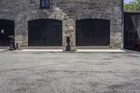 an older stone building with garage doors and two fire hydrants on each side of the driveway