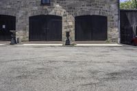 an older stone building with garage doors and two fire hydrants on each side of the driveway