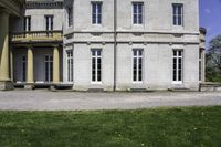 the house is made of stone and has windows and doors, with a black bench in front