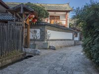 a stone walkway that leads to a white building with red lanterns on it's roof