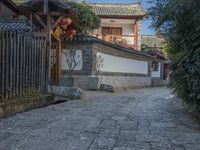 a stone walkway that leads to a white building with red lanterns on it's roof