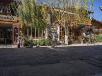 a restaurant on the corner in the town of china with lots of furniture under the tree