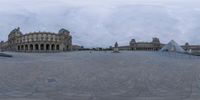 a large courtyard surrounded by old buildings under a cloudy sky with lots of clouds overhead