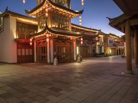 a pagoda sits outside in a building lit up at night and lit up with lanterns