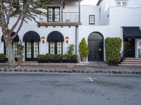 a street scene with focus on the trees and the building that has black awnings and windows