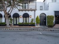 a street scene with focus on the trees and the building that has black awnings and windows