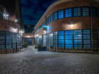 some dark blue windows in an industrial building with no one on the street to the right