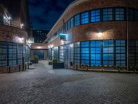 some dark blue windows in an industrial building with no one on the street to the right