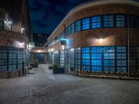 some dark blue windows in an industrial building with no one on the street to the right