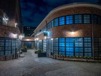 some dark blue windows in an industrial building with no one on the street to the right