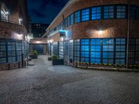 some dark blue windows in an industrial building with no one on the street to the right