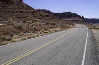 there is a motorcycle on the side of the road with desert in the background and mountains