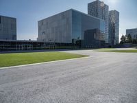 a building is on a sunny day in this photo, there is grass around the concrete area with bushes and buildings