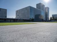 a building is on a sunny day in this photo, there is grass around the concrete area with bushes and buildings