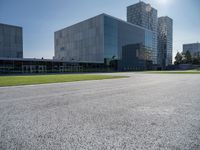 a building is on a sunny day in this photo, there is grass around the concrete area with bushes and buildings