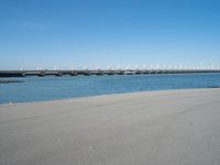 the bridge has two different bridges on it over water or lake side with blue sky in the background