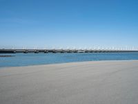 the bridge has two different bridges on it over water or lake side with blue sky in the background