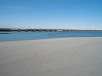 the bridge has two different bridges on it over water or lake side with blue sky in the background