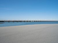 the bridge has two different bridges on it over water or lake side with blue sky in the background