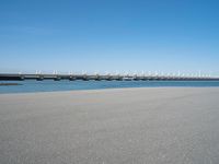 the bridge has two different bridges on it over water or lake side with blue sky in the background