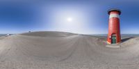 a 360 camera fish eye view of a lighthouse on the beach by a large field