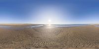 a fish eye view of a beach with a body of water in the distance in front of a sky and some sand on the ground