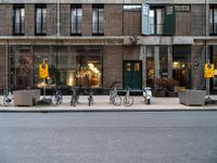 a group of bikes that are by some building facades on a street corner with a man walking next to them