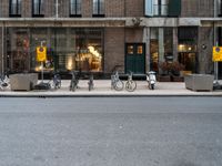 a group of bikes that are by some building facades on a street corner with a man walking next to them