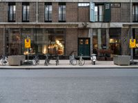 a group of bikes that are by some building facades on a street corner with a man walking next to them