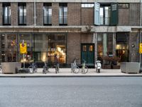 a group of bikes that are by some building facades on a street corner with a man walking next to them