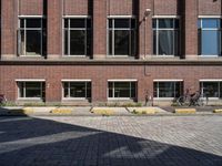 two bicycles are parked in front of a brick building with windows and doors open to let the outside outside light into the sun