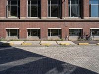 two bicycles are parked in front of a brick building with windows and doors open to let the outside outside light into the sun