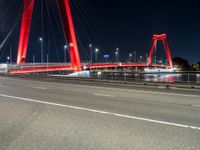 a road with lights on a bridge next to water at night with red columns and white lines