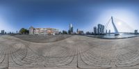 circular panorama photo taken in front of large buildings on a river with a bridge going into the distance