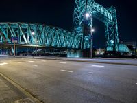 a view of a large bridge and road at night with light trails from the street