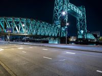 a view of a large bridge and road at night with light trails from the street