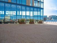 a sidewalk with several benches near tall buildings and blue windows with the word salara on them