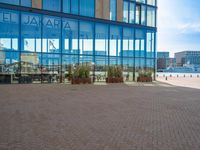 a sidewalk with several benches near tall buildings and blue windows with the word salara on them