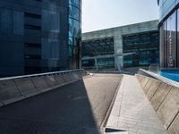 a street near an office building that has an empty sidewalk on one side and a blue building with lots of windows