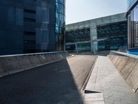 a street near an office building that has an empty sidewalk on one side and a blue building with lots of windows