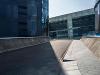 a street near an office building that has an empty sidewalk on one side and a blue building with lots of windows